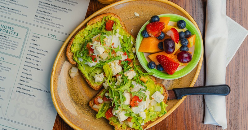 Avocado toast with a bowl of fruit
