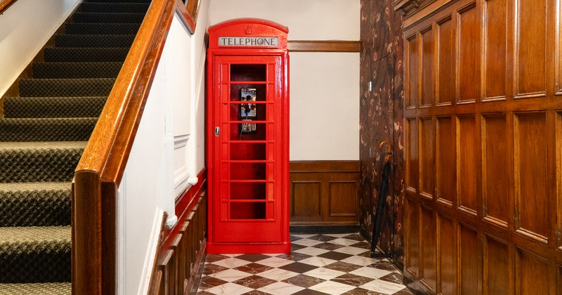 A red telephone booth in the corridor at the entrance to the bar and stairs