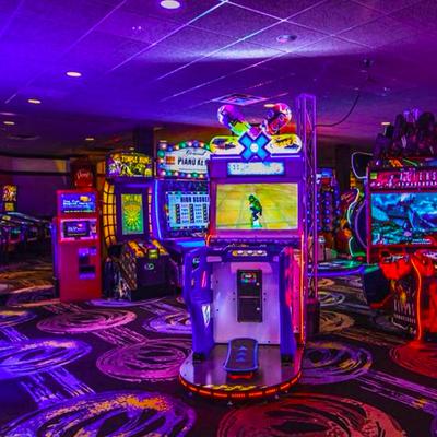 Colorful arcade room filled with various glowing video game cabinets and patterned carpet.