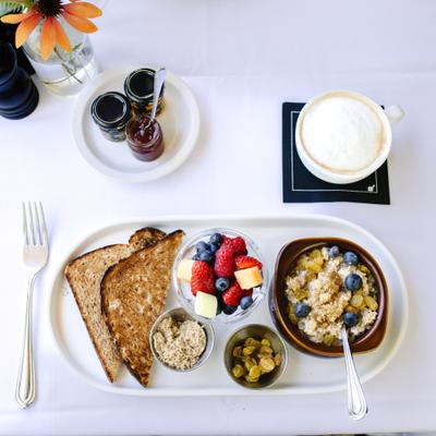 Breakfast tray with toast, oatmeal, fresh fruit, coffee, and jam.