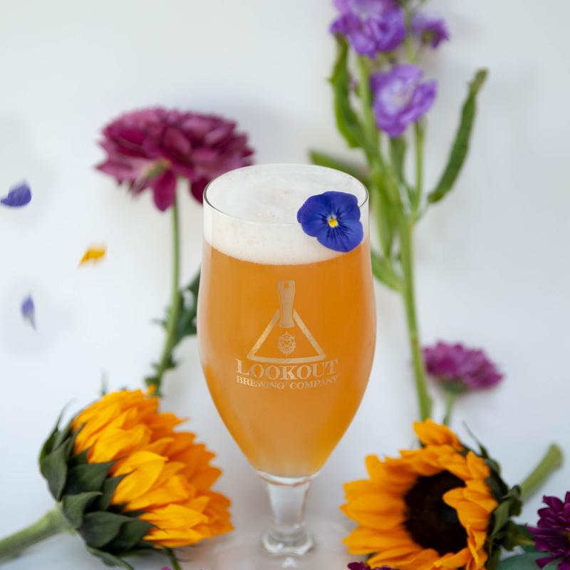 Decorative glass of foamed beer garnished with flowers.