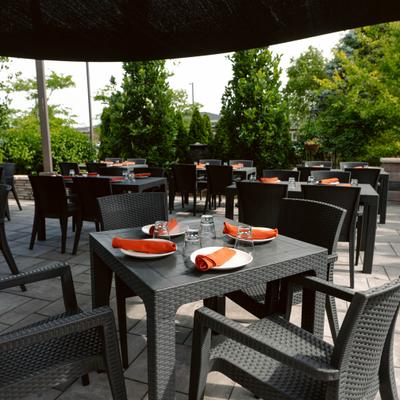Outdoor patio with tables set for dining, surrounded by lush greenery.