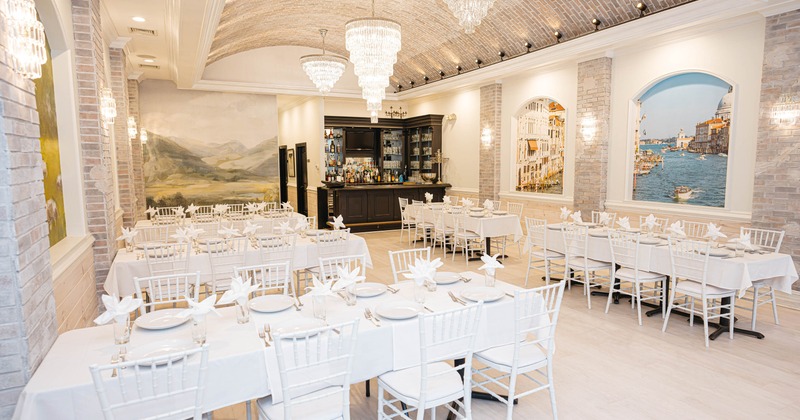 Interior, dining area with white-draped tables, chandeliers, and wall murals