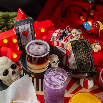 Spooky-themed table setup featuring layered and colored Halloween cocktails.