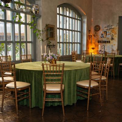Interior with round wedding reception tables with chairs and large windows.