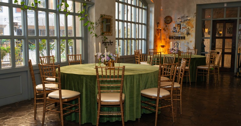 Interior, seating area, green cloth round tables for ten, large arched windows