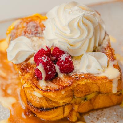 Creme brulee French toast, topped with whipped cream and raspberries.