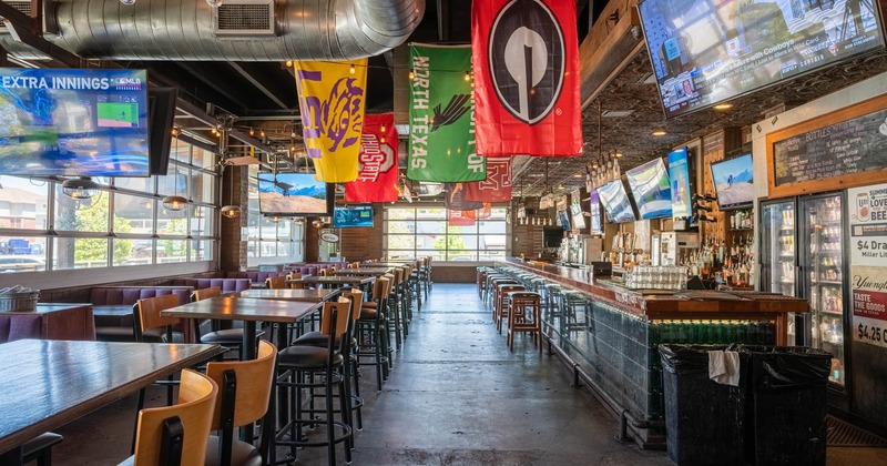 Interior, bar and seating area with lots of TV screens and banners hanging from the ceiling