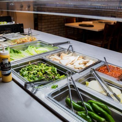 Self serve bar with vegetables and sauces.