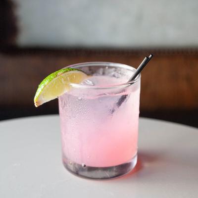 A refreshing pink cocktail in a short glass garnished with a lime wedge