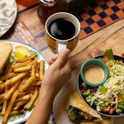 Customer having culb sandwiches with fries, salad, and a cup of coffee.