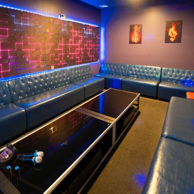 A lounge with blue sofas, a table, neon lights, and wall art.