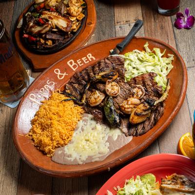 Grilled steak topped with grilled shrimp, onion, jalapeno, lettuce with dressing, rice, and beans.