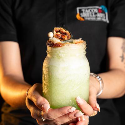 A person holding a refreshing drink with fruit garnish.