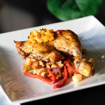 Roasted chicken served over sautéed vegetables and diced potatoes on a square plate.