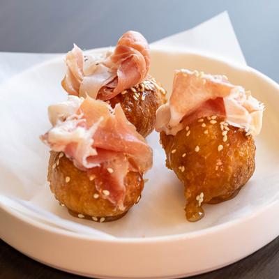 Fried dough balls, topped with shaved ham.