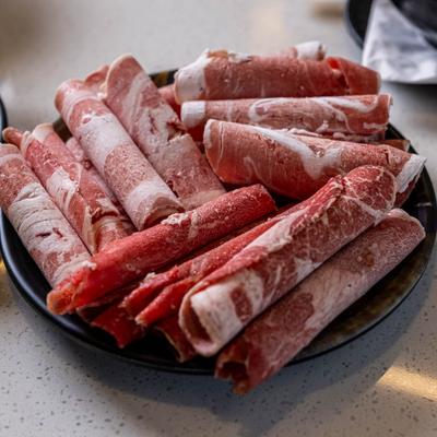 Rolled raw beef brisket served on a black plate.
