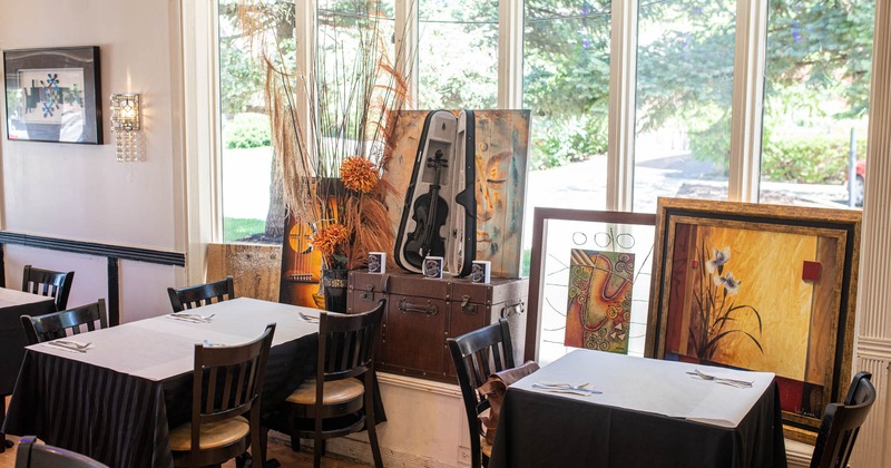 Interior, dining tables, paintings leaned against the window