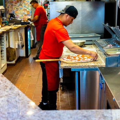 A pizza maker preparing a pizza in the restaurant.