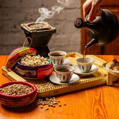 A hand pouring coffee in cups, served drinks and food.