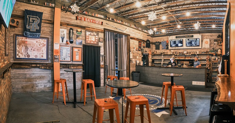 Interior, round orange tables and black chairs, bar in the back
