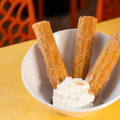 Churros served in a bowl with whipped cream.