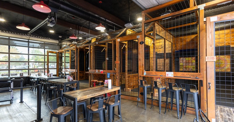 Interior of an ax-throwing venue with wooden enclosures and tables