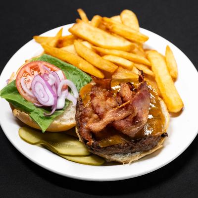 Bacon cheese burger with lettuce, onion, and tomatoes, served with a side of french fries..
