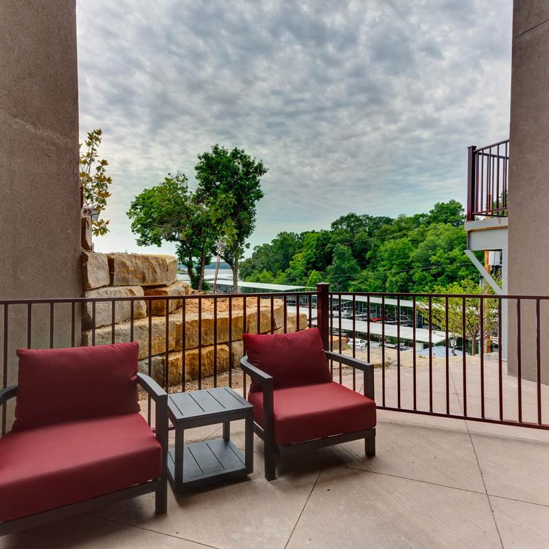 Armchairs and a small table outside on the balcony.