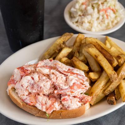 Lobster roll served with fries and coleslaw.
