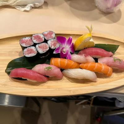 Variety of tuna and salmon nigiri along with tuna maki rolls, served on a wooden tray.