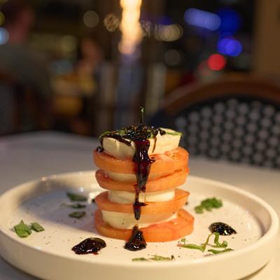 A Caprese salad with stacked layers of fresh mozzarella, tomatoes, and balsamic reduction.