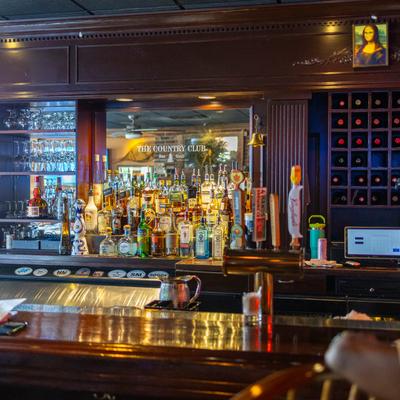 Bar area with a wooden counter, liquor bottles, and glassware.