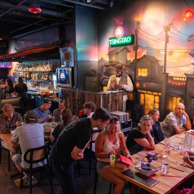 Interior featuring crowd seated at tables with artistic mural decorations on the walls.
