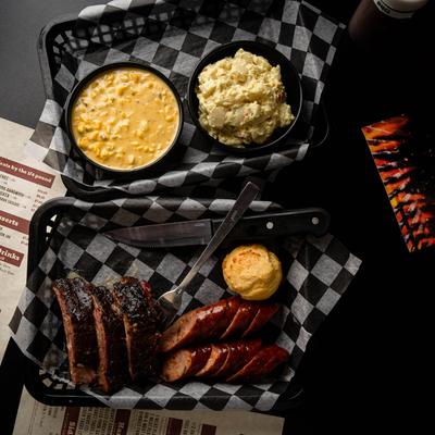 Meat platter with sides and menu on a table, top view.