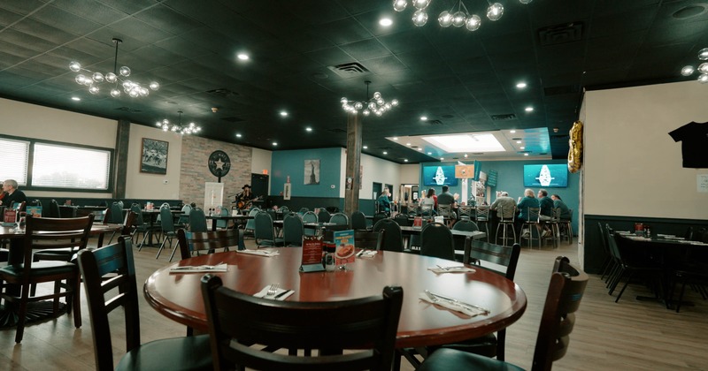 Interior of a spacious modern restaurant with tables, chairs, and decorative lighting