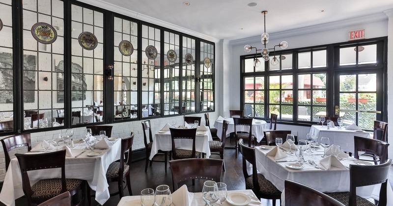Interior, dining area, white cloth tables with wooden chairs, ready for guests, patio door