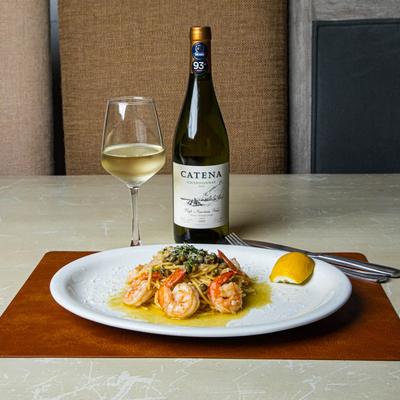 Shrimp scampi plate paired  with a glass and bottle of white wine.