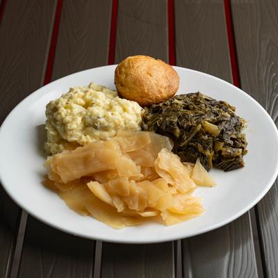 Sweet cabbage served on the plate with potato salad, cornbread and collard greens.