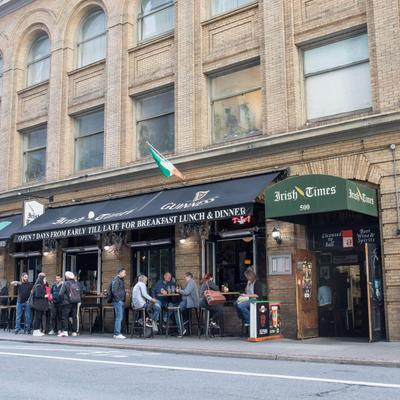 Street view of the pub with people sitting and standing outside.