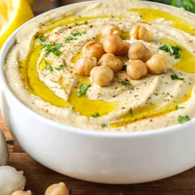 Creamy hummus topped with chickpeas, olive oil drizzle, and herbs.