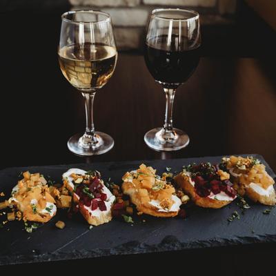 Beet bruschetta served with glasses od red and white wine.