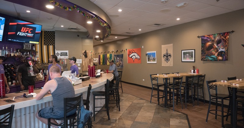 Bar area, bar, bar stools, tables, people seating
