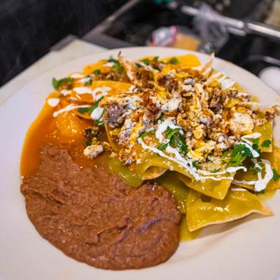 Chilaquiles with various toppings, served with refried beans.