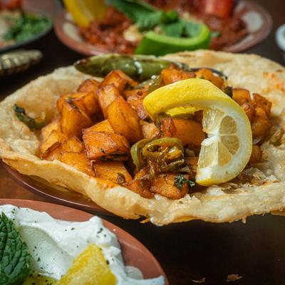 A crispy flatbread topped with spiced potato cubes, surrounded by assorted foods.