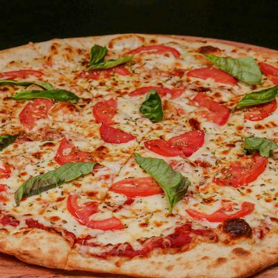 Margherita pizza topped with cheese, sliced tomatoes and basil.