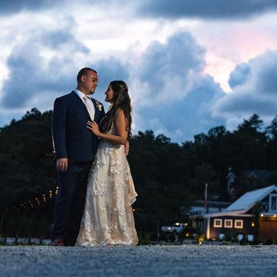 A wedding couple share an intimate moment against a dramatic evening sky