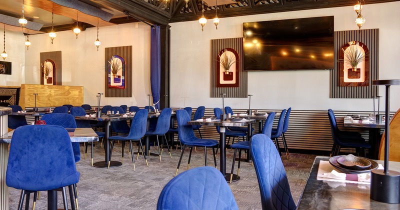 Modern and cozy restaurant interior dining area with elegant blue velvet chairs and set tables