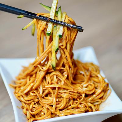 Chopsticks holding noodles over a bowl.