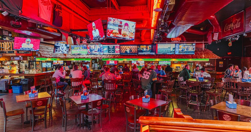 Inside, numerous TV screens showing sports games, and customers seated at wooden tables